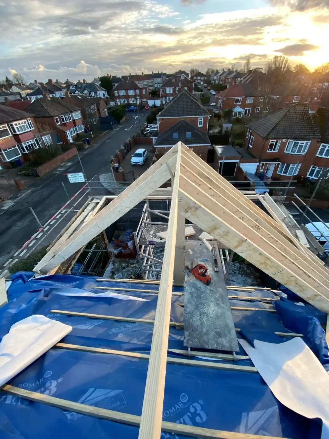 Hand-cut timber rafters rising to a hip over a house extension