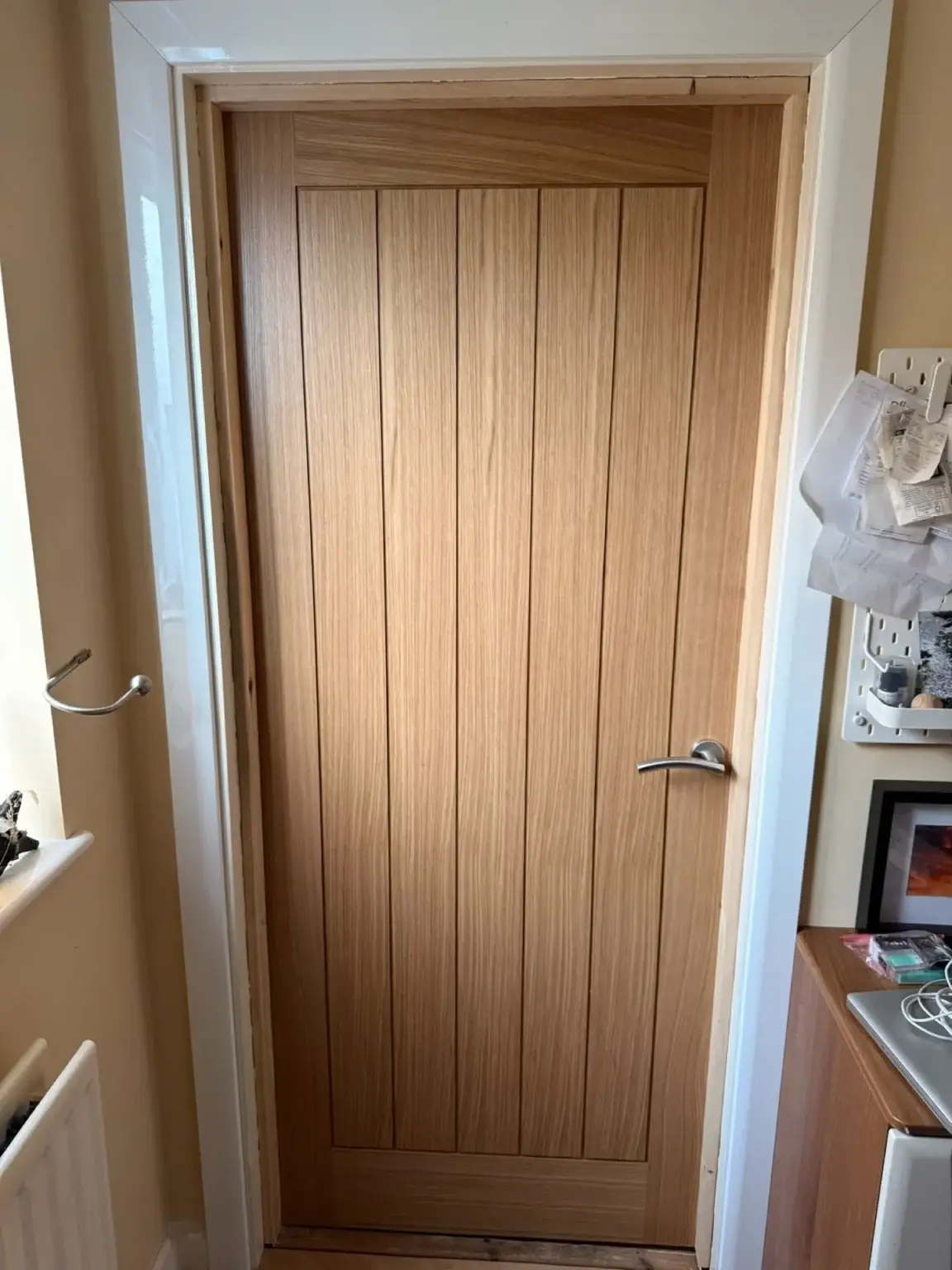 An oak internal door hung in a white painted frame