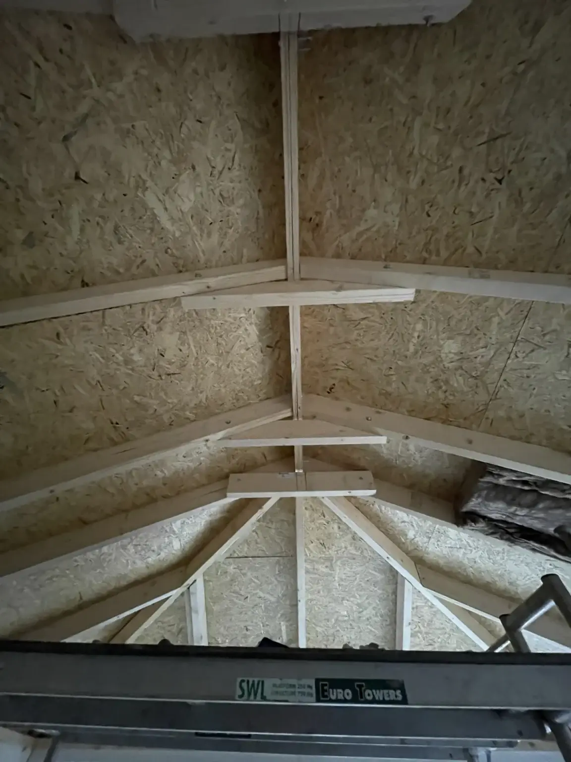 The underside of a new pitched warm roof, with timber rafters and boarding