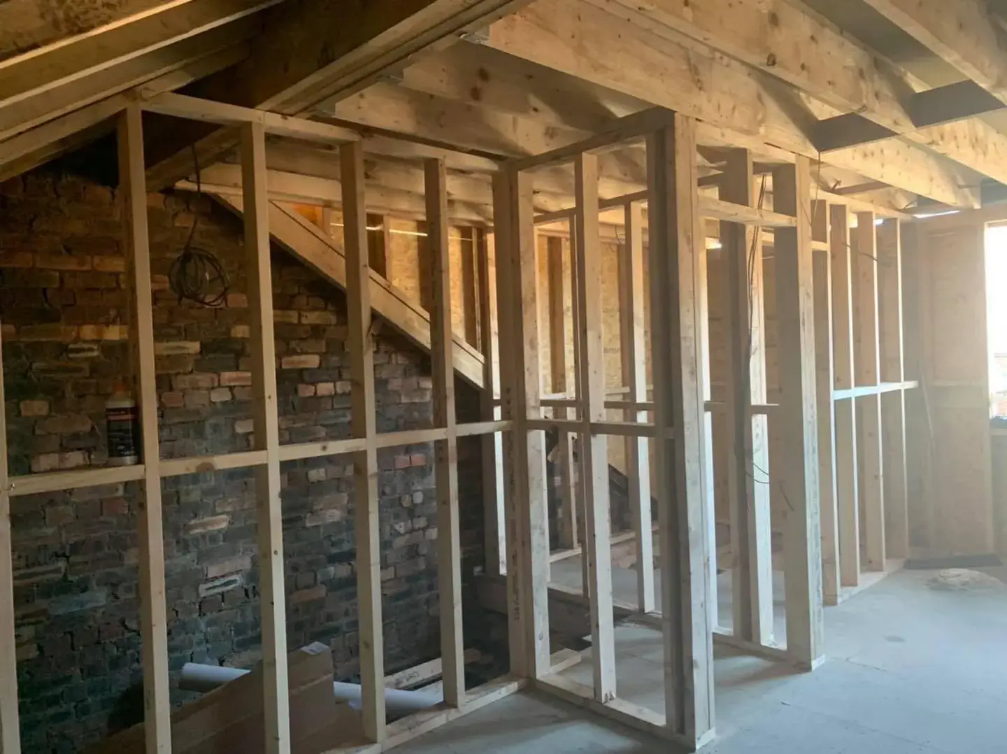 Timber stud walls framed out inside a room with exposed brick