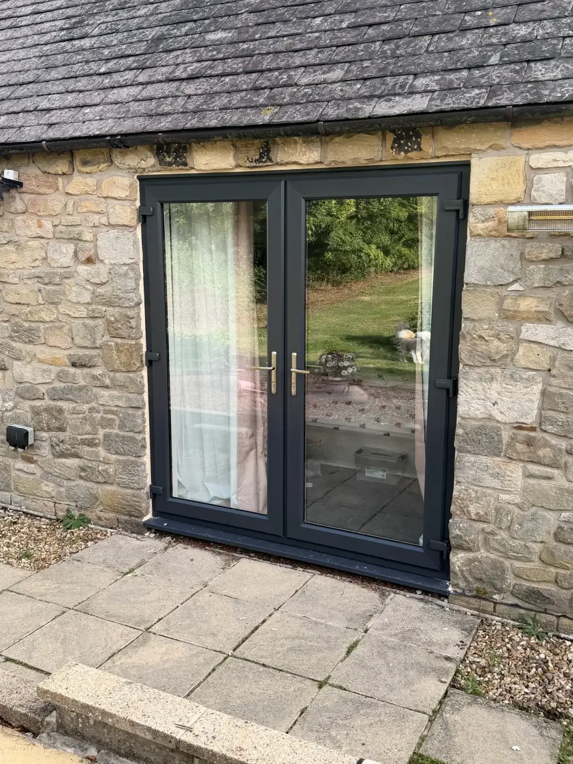 Anthracite grey French doors fitted in a stone cottage wall