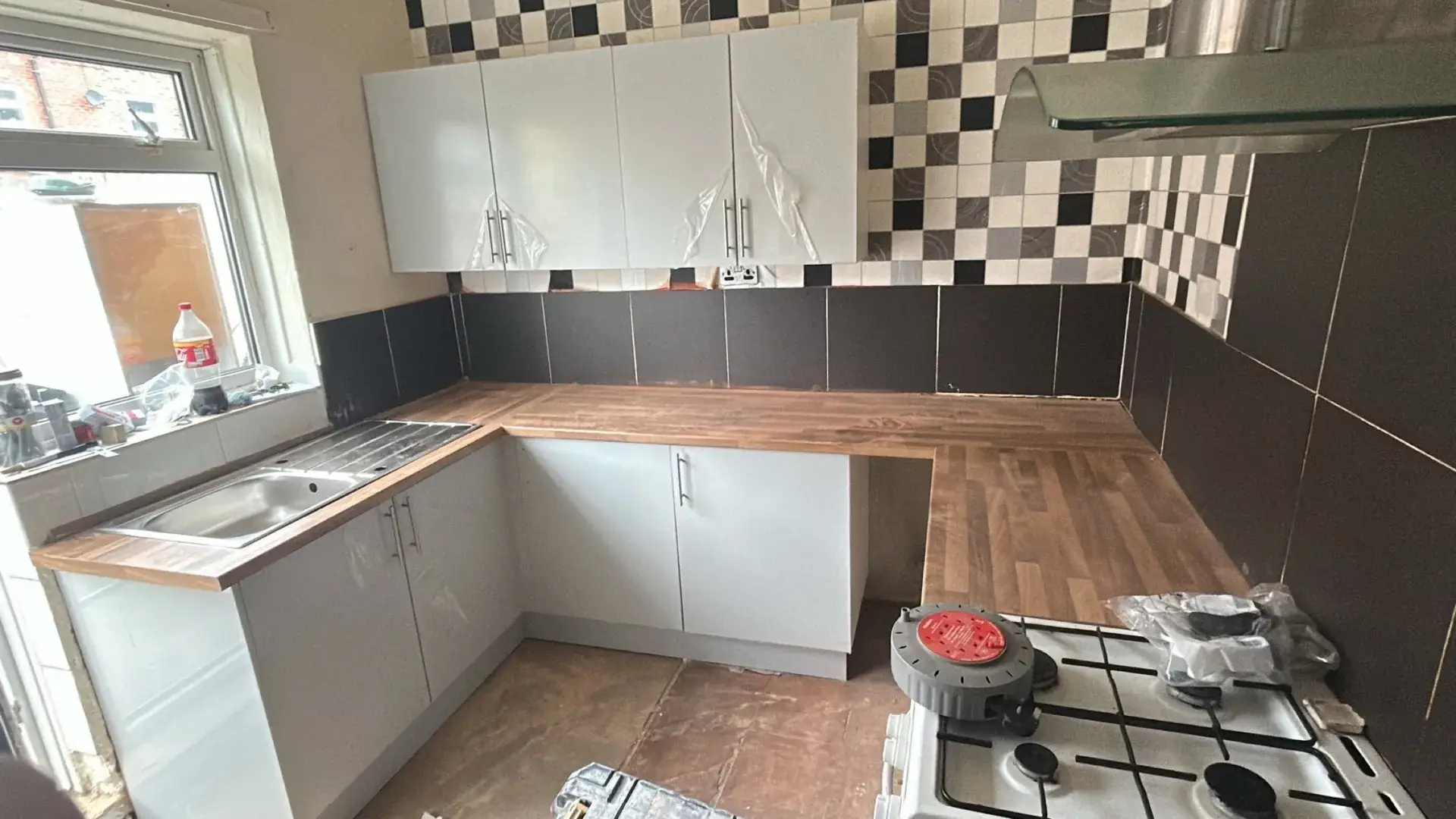 A fitted L-shaped kitchen with a wood-effect worktop