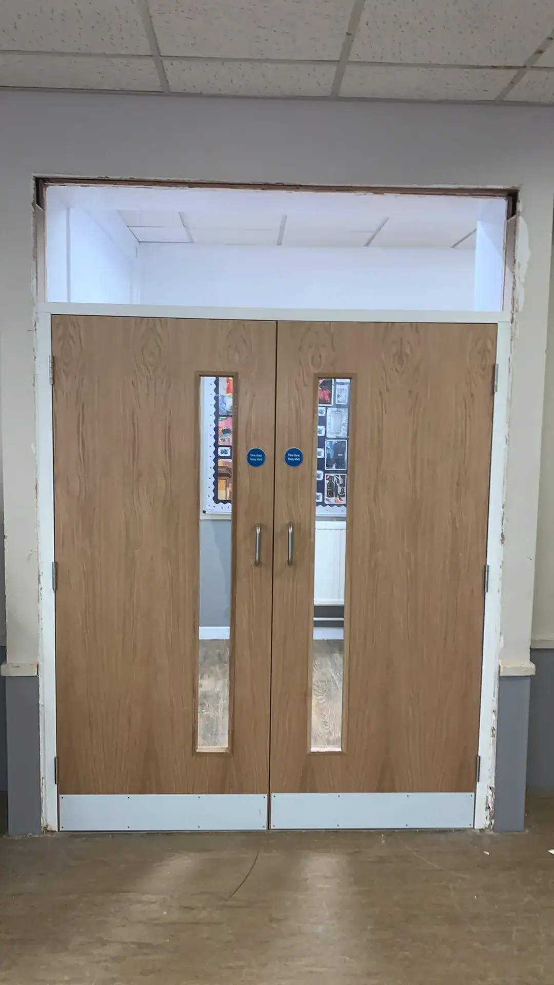 Oak-veneer double doors with vision panels under a glazed fanlight