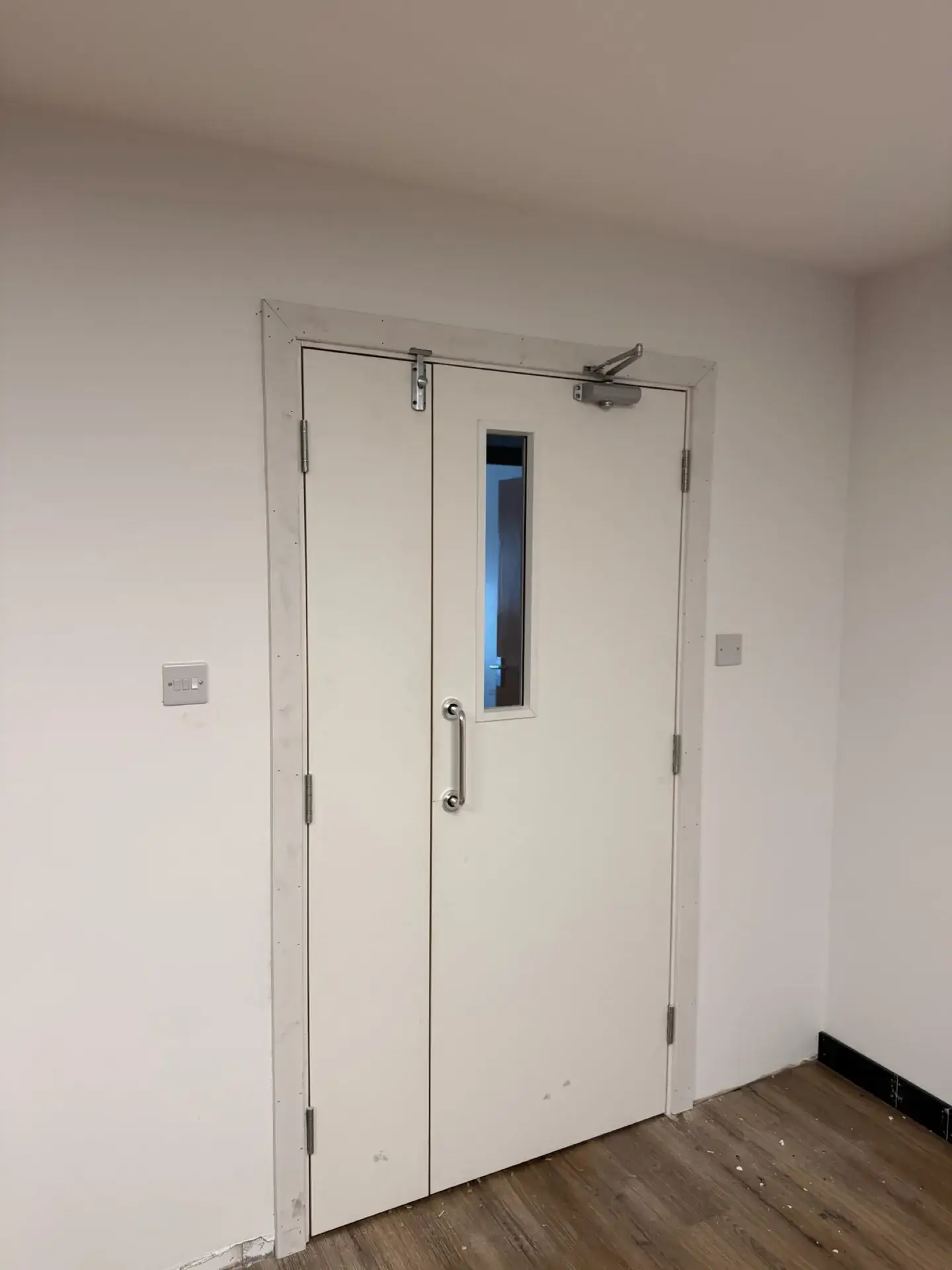 White double doors with a vision panel and a closer