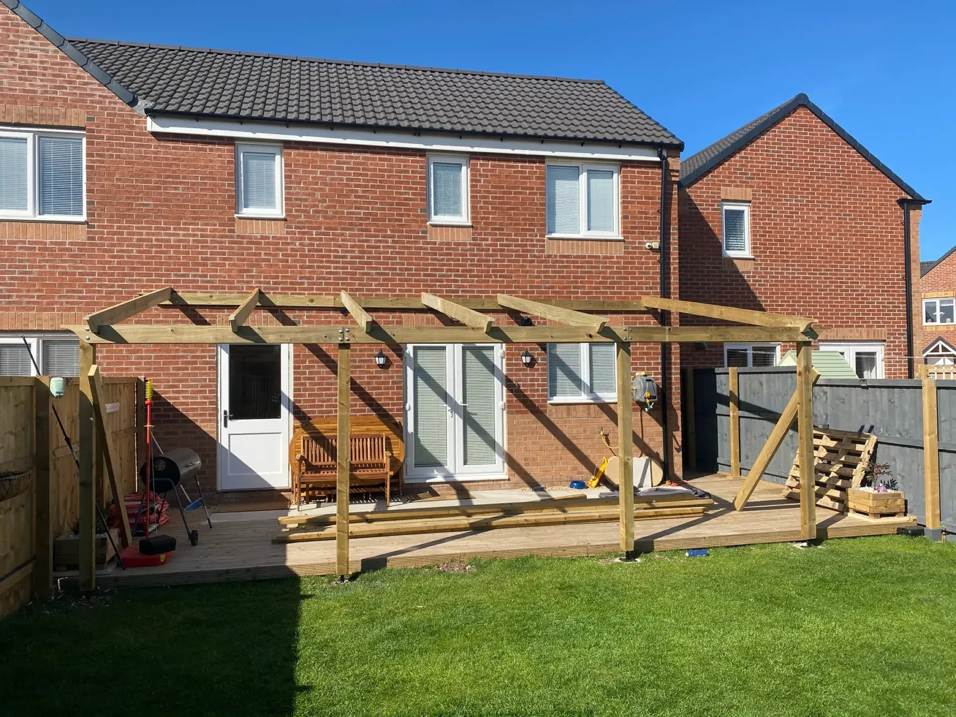 A timber pergola over a new deck behind a new-build house