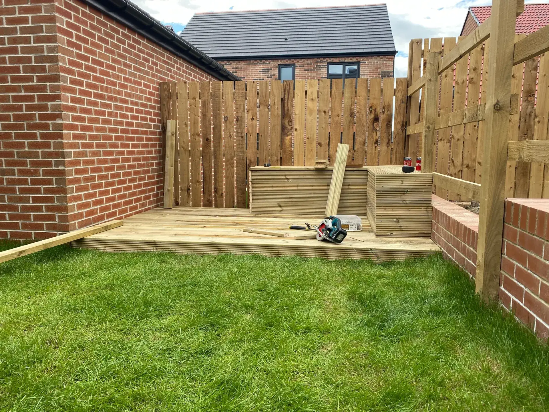 A slatted timber screen with raised sleeper planters on gravel