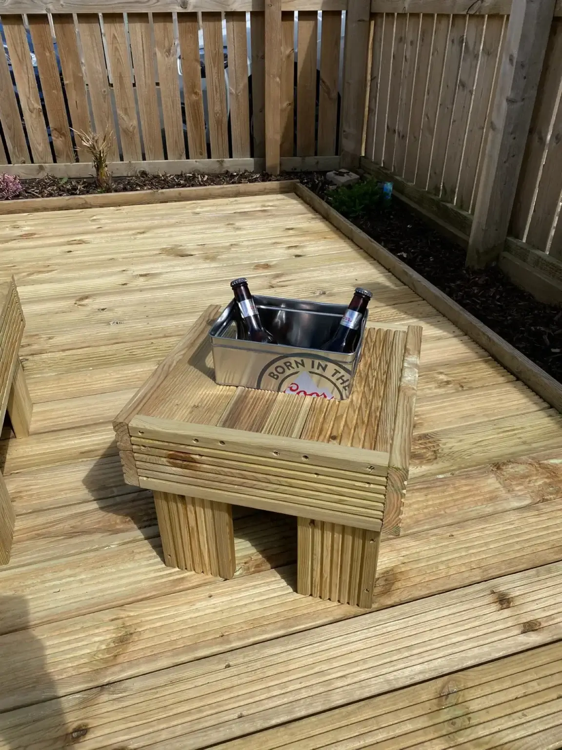 A small built-in timber table with a drinks cooler, on a timber deck