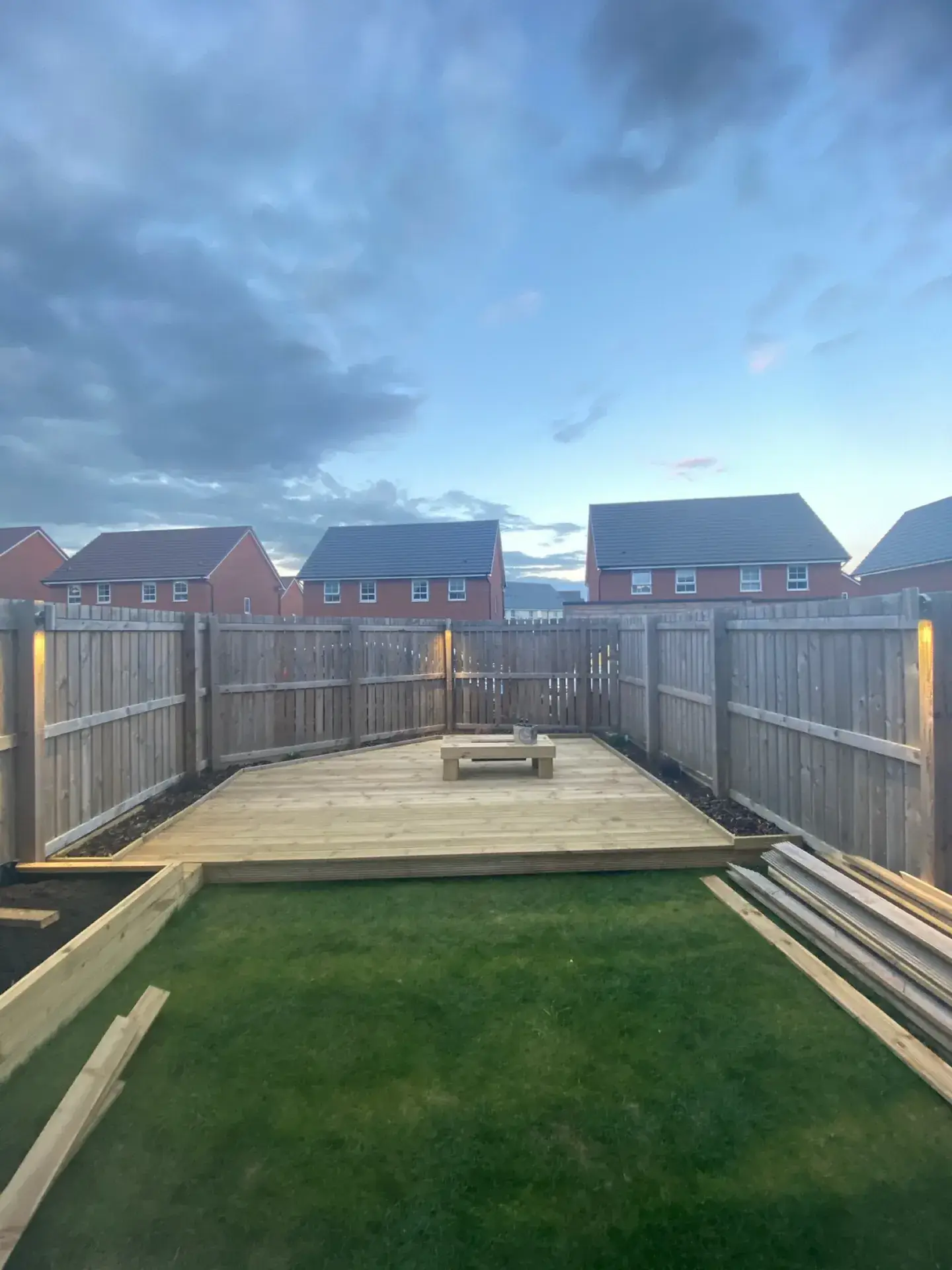 A timber deck with a built-in bench and table at the end of a lawn