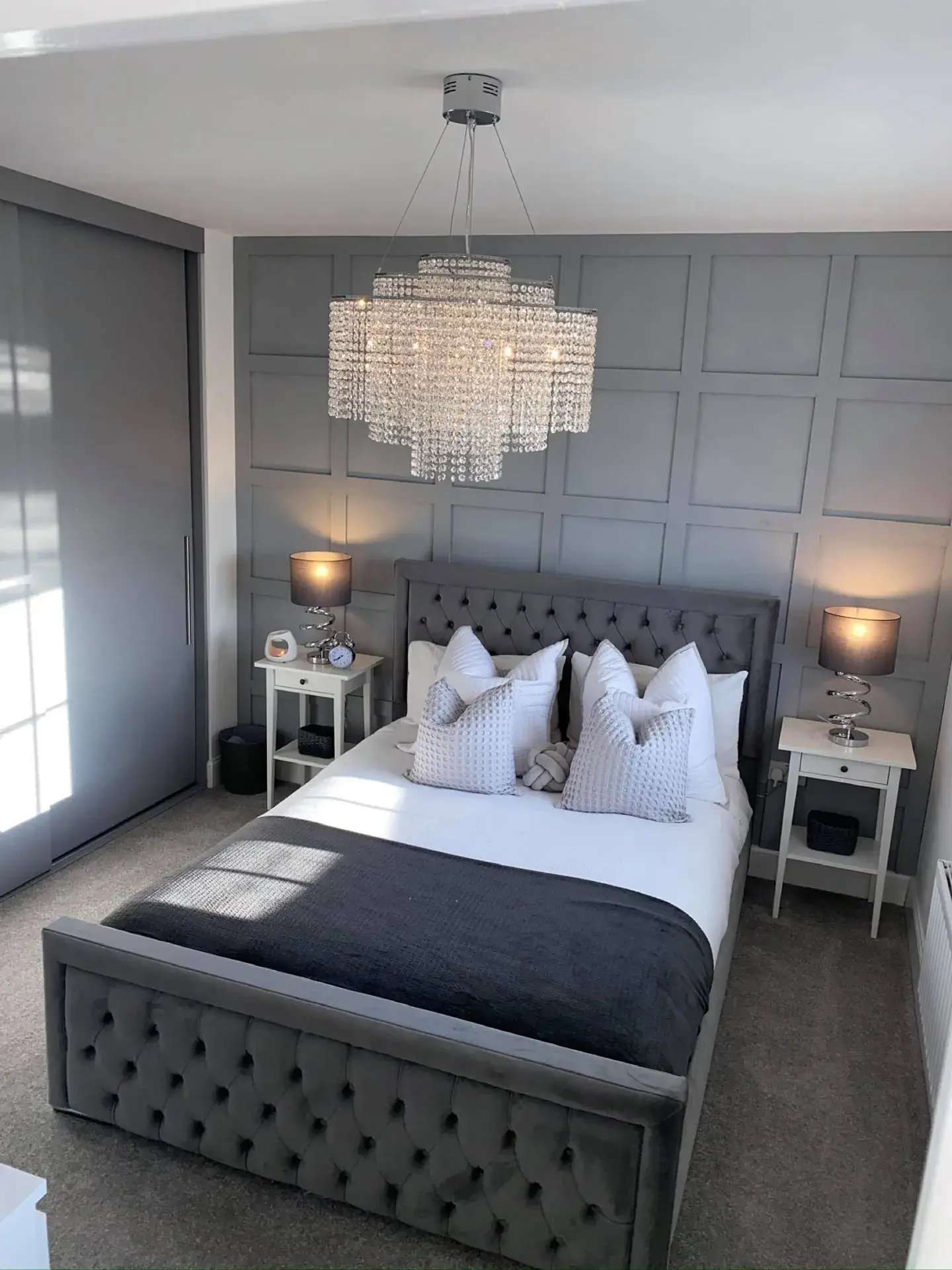 A bedroom with a grey panelled feature wall behind the bed
