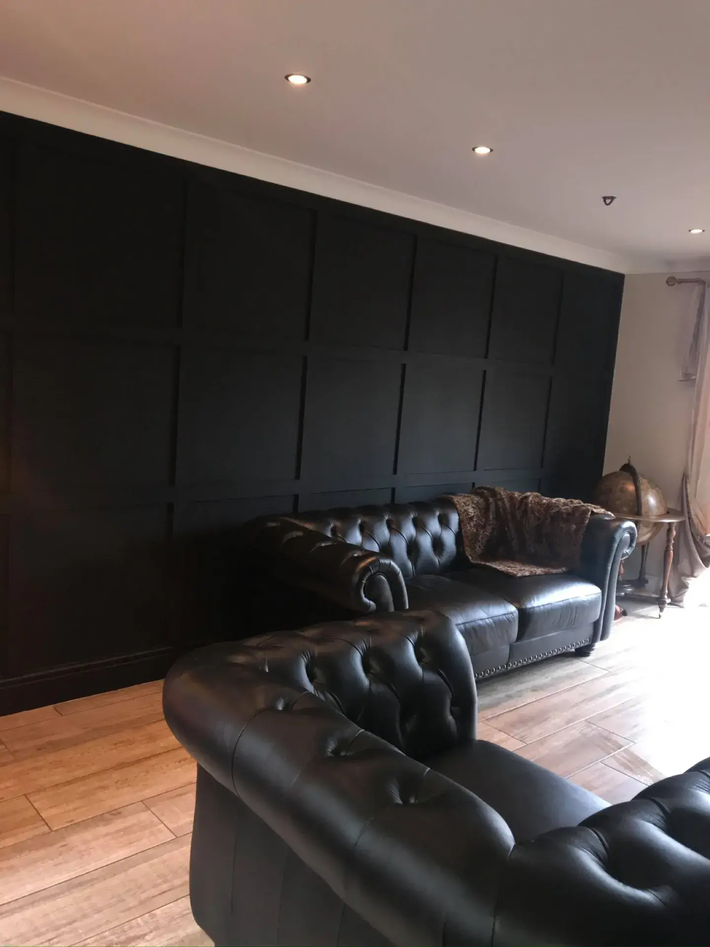 A living room with a dark panelled wall and leather sofas