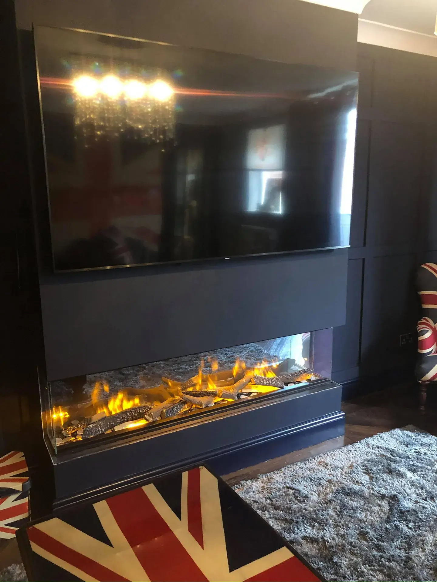 A dark panelled wall with a built-in electric fire and a television