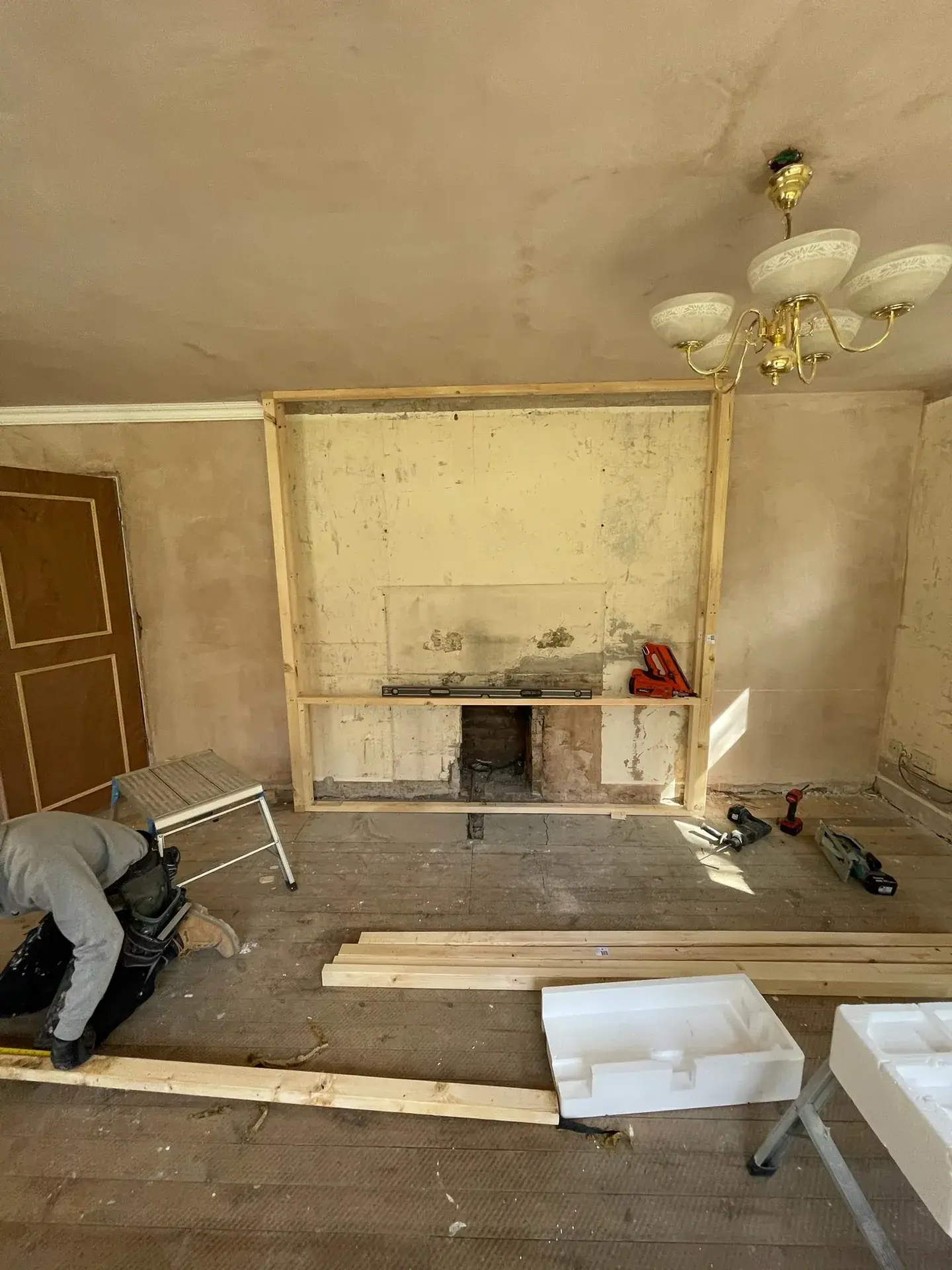 A room stripped back, with a timber frame going up around an old fireplace