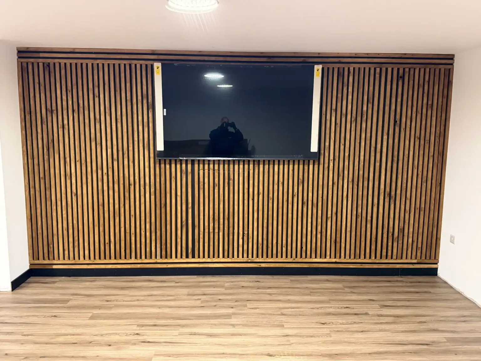 A slatted timber media wall around a wall-mounted television