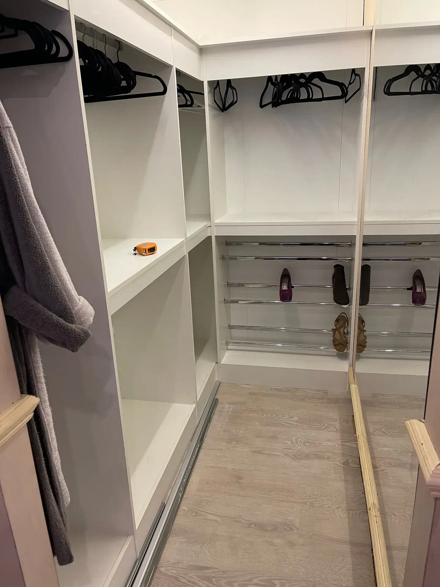 A walk-in wardrobe with hanging rails and shelving, part way through fitting